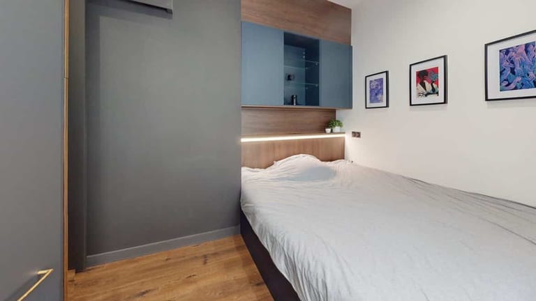 Chambre Airbnb sur mesure Gabriel Orléans : tête de lit chêne, rangements suspendus bleu canard, bandeau LED encastré